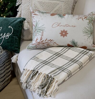 Bild på mysigt soffhörn med pläd, kuddar och juldekorationer