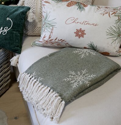 Bild: Olivgrön pläd med snöflingor i soffhörna