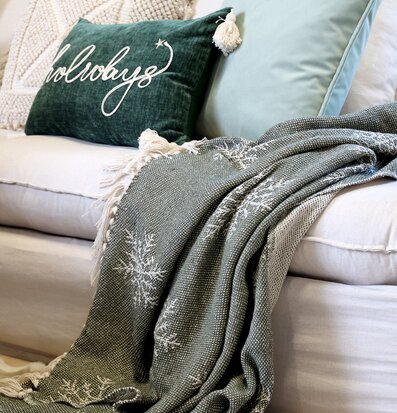 Bild: Inbjudande soffa med olivgrön pläd och textilvariation