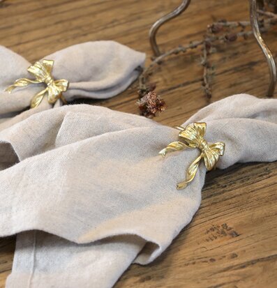 Bild med linneservetter och mässingsrosett på rustikt träbord