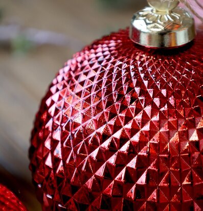 Bild på röd julkula med geometriskt mönster och glittrande yta