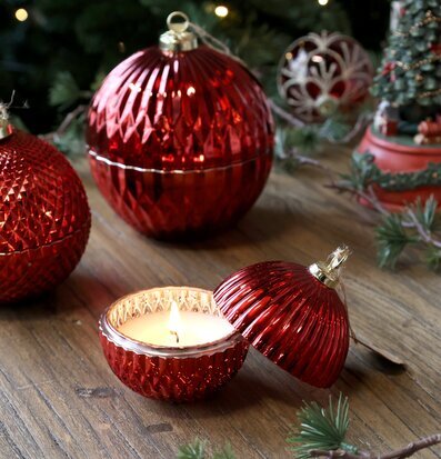 Bild av röd julkula med ljus på trägolv i vintrig miljö