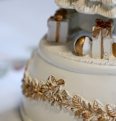 Bild av detaljrik juldekoration i creme och guld med paket