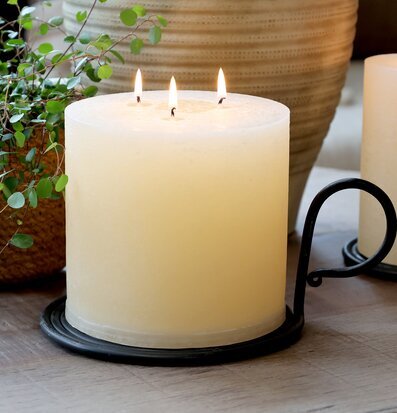 Bild på stor kammarljusstake med blockljus och grön växt