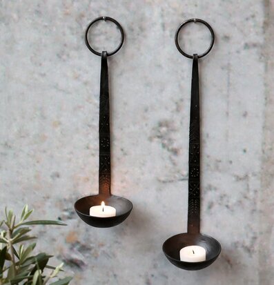 Bild på två antiksvarta väggljusstakar med tända värmeljus