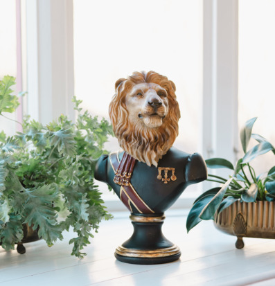 Bild på lejonbyst i ljus inredning med växter och medaljer