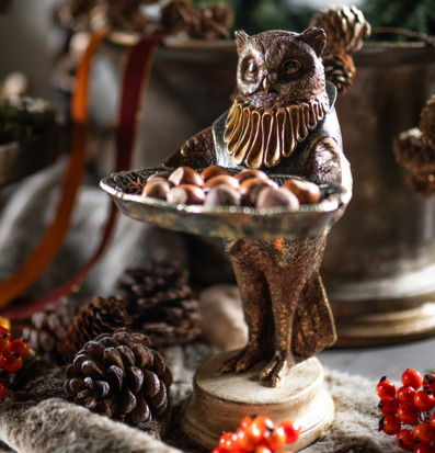 Bild på dekorativ uggla med fat och naturinspirerat stilleben