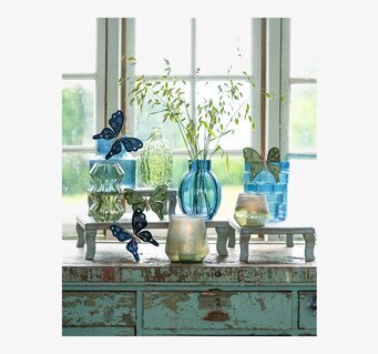 Bild med piedestalbord, antik byrå och blågröna glasvaser