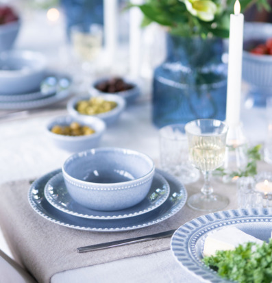 Bild av dukat bord med blå keramik, linne och levande ljus