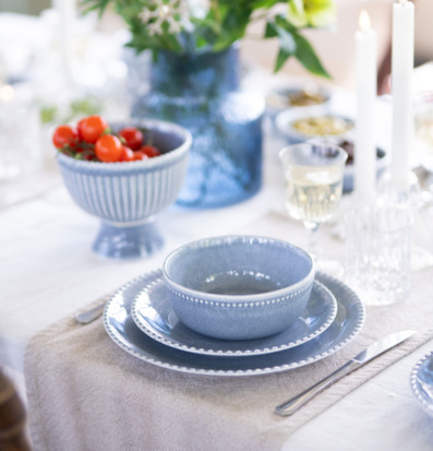 Bild av dukat bord med blå servis, linne och grönskande vas