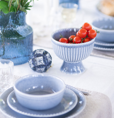 Bild av harmonisk blå dukning med skål på fot och tomater