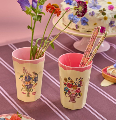 Bild av färgglad fikadukning med blommiga muggar och tårta