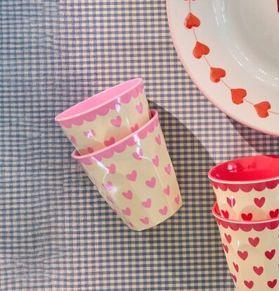 Bild på färgglada hjärtmuggar och tallrik på rutigt tyg