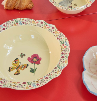 Bild av färgstark dukning med blommiga skålar och croissant