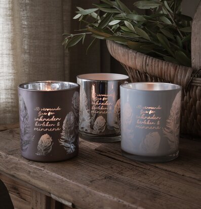 Foto: Tre ljuslyktor med fjädermotiv på träbordet