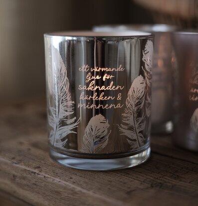 Foto: Rökfärgad glaslykta med fjädrar och text