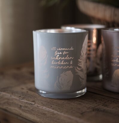 Foto: Ljuslykta i frostat glas med text och fjädrar