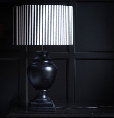 Foto av svart bordslampa med randig skärm i mörker