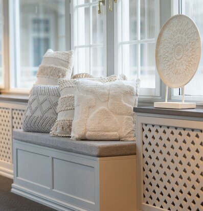 Foto: Ljust fönster med sittbänk och ornamentstativ