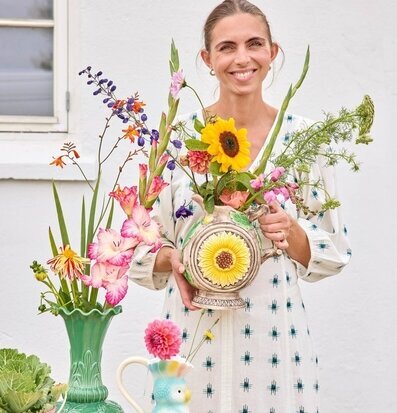 Foto: Person med solrosvas och färgstark bukett inomhus