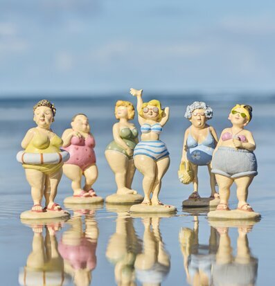 Bild på strandfigurer med spegling vid havet i sommar