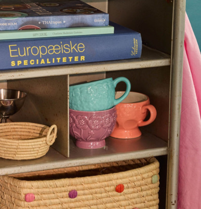 Foto av metallhylla med kokböcker och färgkoppar