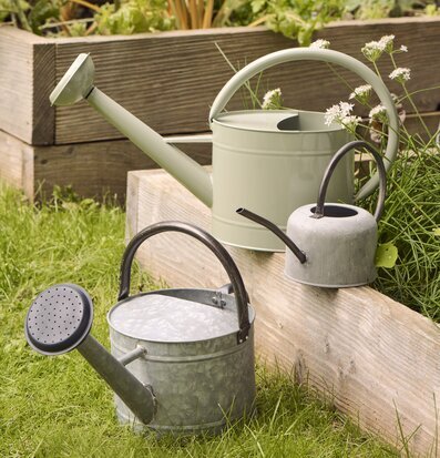 Foto av grå vattenkanna i trädgård med odlingslåda