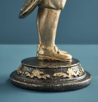 Foto av statyben i antikguld på ornamenterad sockel