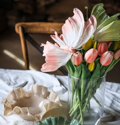 Foto: Tulpaner i glasvas på dukat bord, stilleben