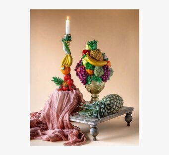 Foto av fruktkorg i guld med frukt och ljusstake