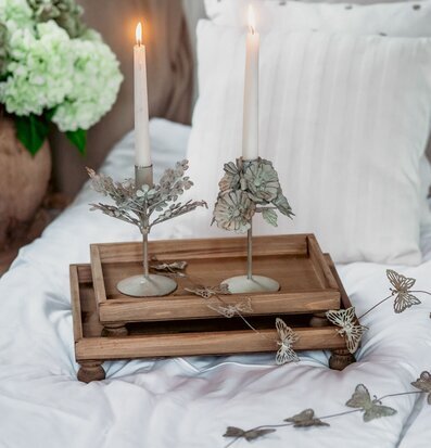 Foto: Träbrickor på säng med tända ljus och fjärilar