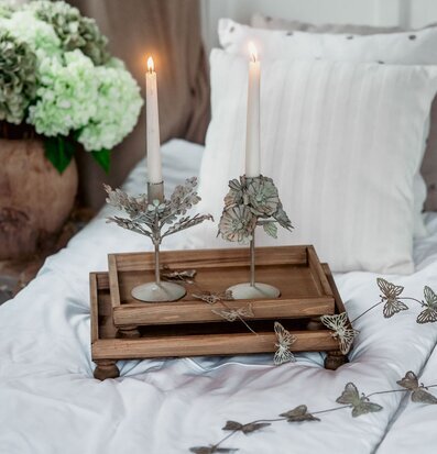 Foto: Piedestalbrickor i trä på bäddad säng med ljus