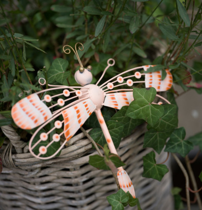 Foto: Dekorativ trollslända i metall bland gröna blad