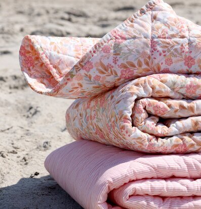 Foto: Randig och blommig quiltad pläd på strand