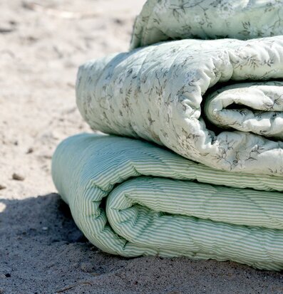 Foto: Hoprullade gröna plädar på sandstrand utomhus