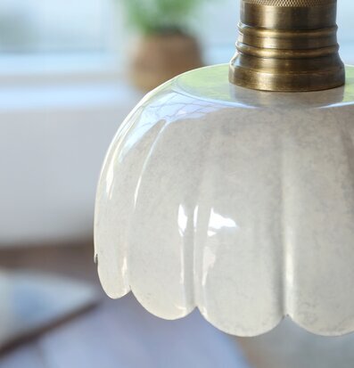 Foto på cremefärgad fönsterlampa med mässingsfäste