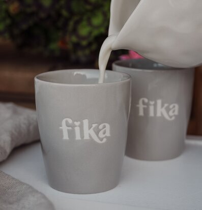 Foto: Grå mugg med fika-tryck och mjölkkanna i kök