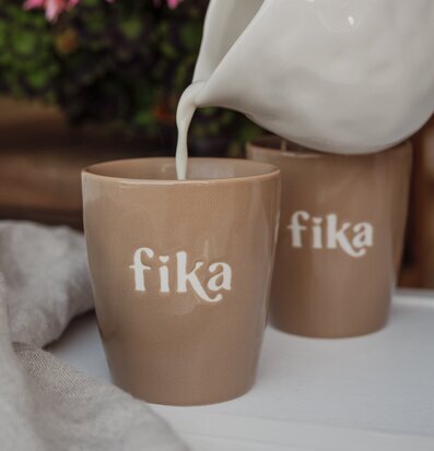 Foto: Fikamugg med kanna som häller dryck vid dukning