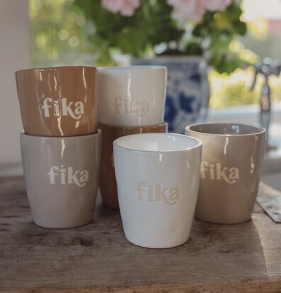 Foto: Keramikkoppar med fika-relief på träbricka
