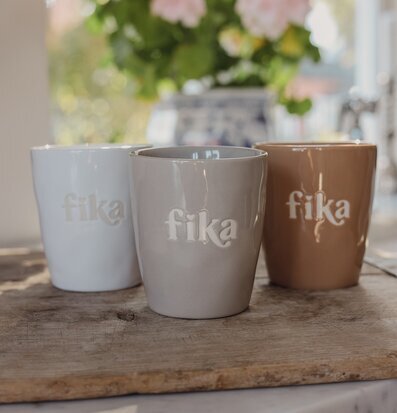 Foto: Keramiska muggar med fika-text på skärbräda