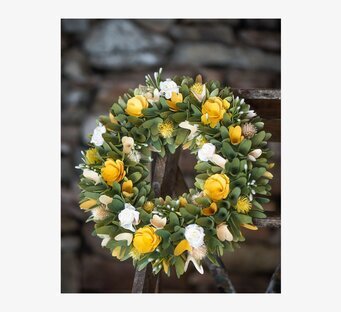 Foto av dörrkrans med gula rosor och gröna blad