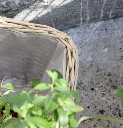 Foto på flätad kruka med plastinsats mot betong