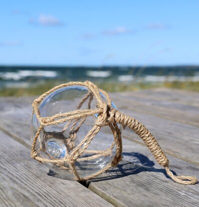 Foto: Glasflöte i repnät på brygga vid havet
