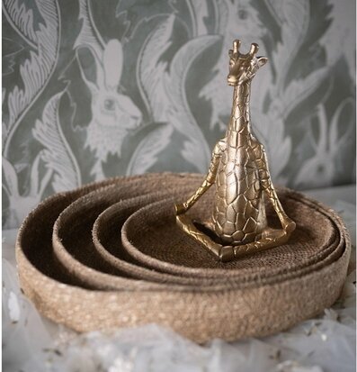 Foto: Sittande guldfärgad giraff på runda korgar