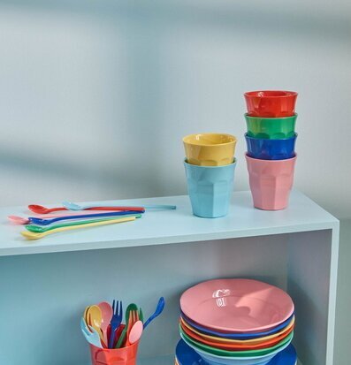 Bild på färgstarka melaminmuggar och servis i hylla