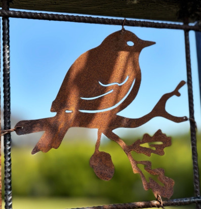 Foto: Rostig metallfågel på armeringsnät med eklöv