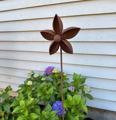 Bild av rostig blomdekoration på stav i plantering