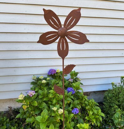 Foto: Rostfärgad metallvindsnurra i trädgårdsmiljö