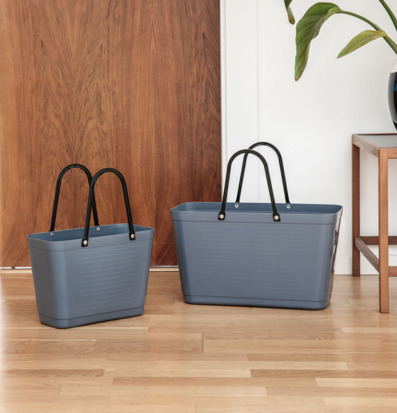 Foto på två duvblå plastväskor på trägolv inomhus