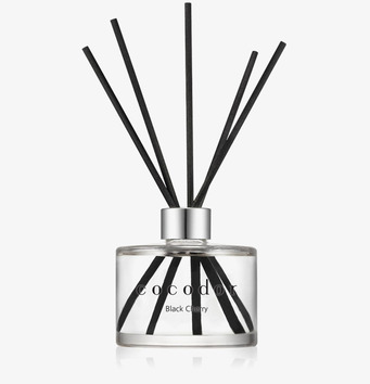 Foto av doftpinnar i glasflaska mot vit bakgrund